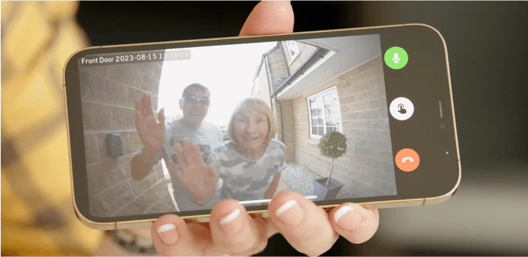 A homeowner using a smartphone to see and speak to visitors at the front door
