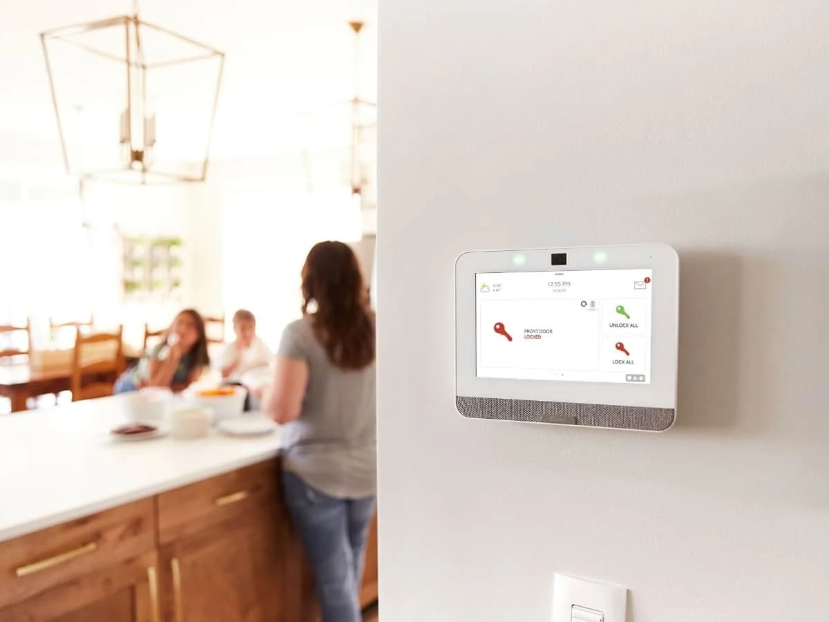 One white Qolsys IQ4 control panel mounted beside a family kitchen