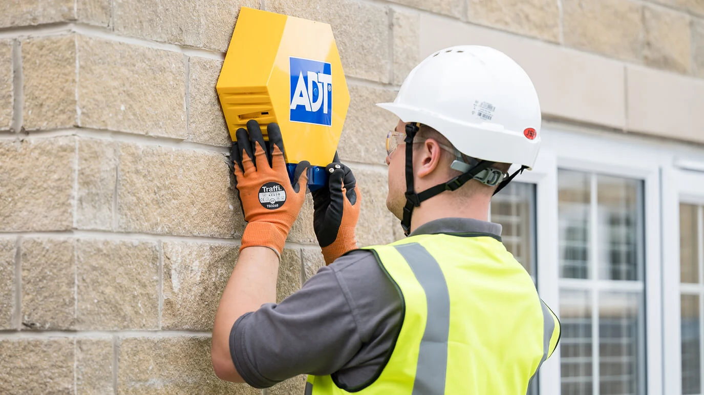 ADT engineer fitting the familiar yellow box to a home